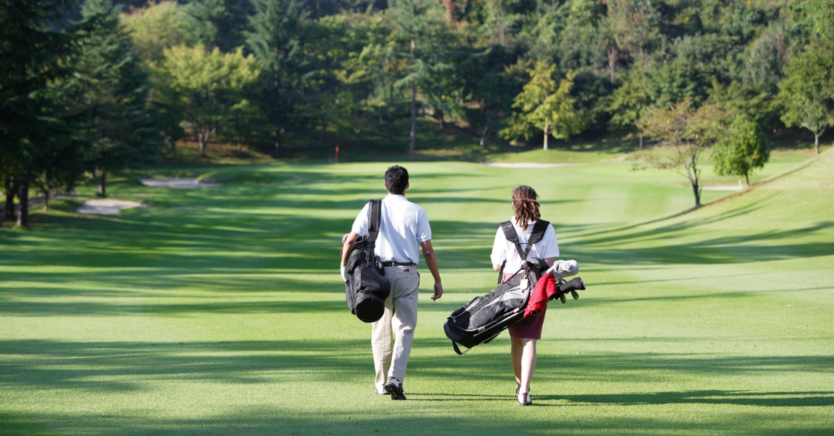 Two golfers walking on a course to stay active and prevent golf back pain